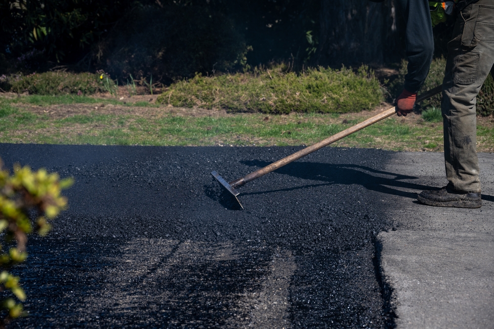 Construction,worker,with,asphalt,rake,smoothing,out,fresh,blacktop,on